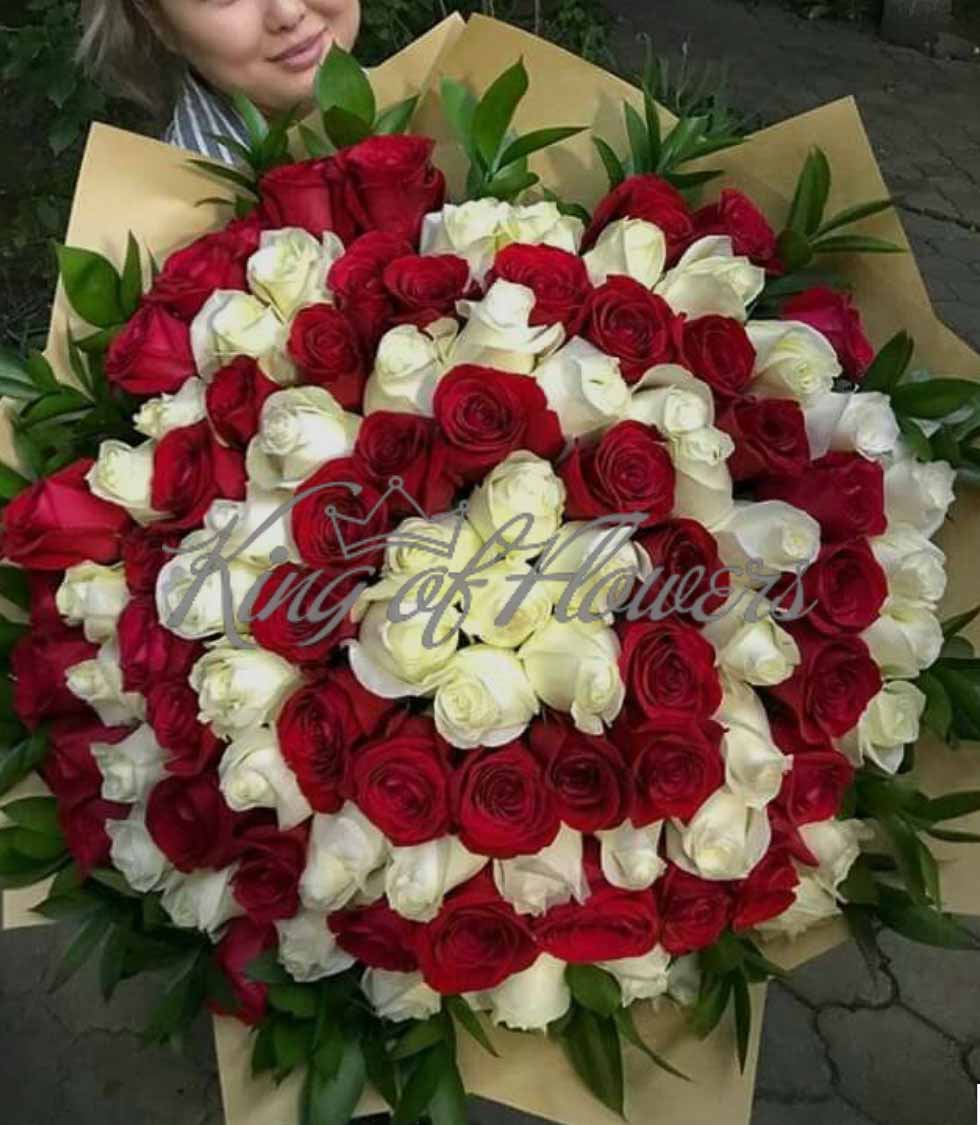Букет из красных и белых роз с зеленью в упаковке