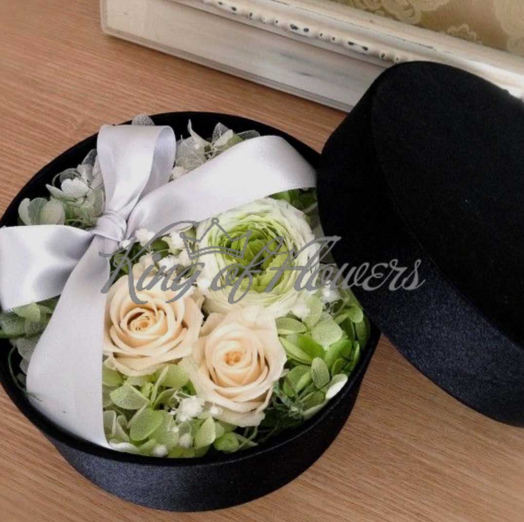 Композиция из ранункулюса, рози зелени в круглой шляпной коробке